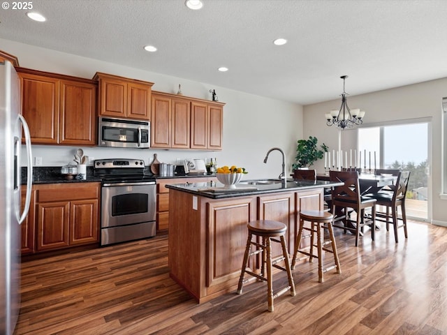 4257 SE Jetty Ave, Lincoln City, OR 97367 - kitchen featuring a sink, stainless steel appliances, brown cabinetry, dark wood-type flooring, and a breakfast bar