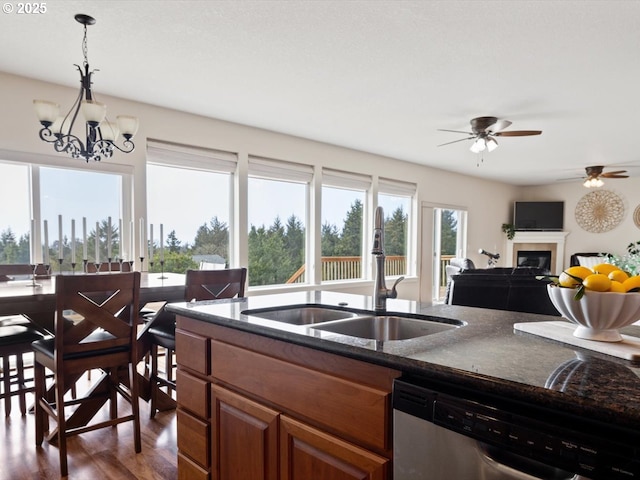 4257 SE Jetty Ave, Lincoln City, OR 97367 - kitchen with brown cabinetry, ceiling fan with notable chandelier, dishwasher, a glass covered fireplace, and a sink