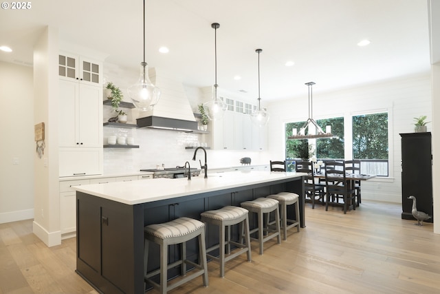 1931 13th St, West Linn, OR 97068 - kitchen featuring open shelves, custom range hood, backsplash, light wood-type flooring, and light countertops