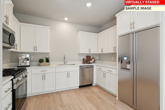 kitchen with sink, light hardwood / wood-style floors, white cabinets, and appliances with stainless steel finishes