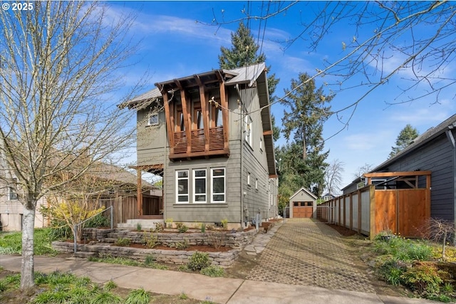 view of front of property featuring fence, an outdoor structure, and a balcony