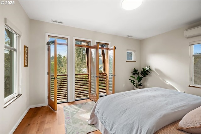 bedroom featuring visible vents, access to exterior, multiple windows, and wood finished floors