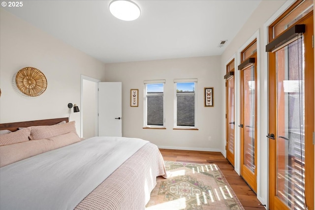 bedroom with baseboards, light wood-style floors, visible vents, and french doors