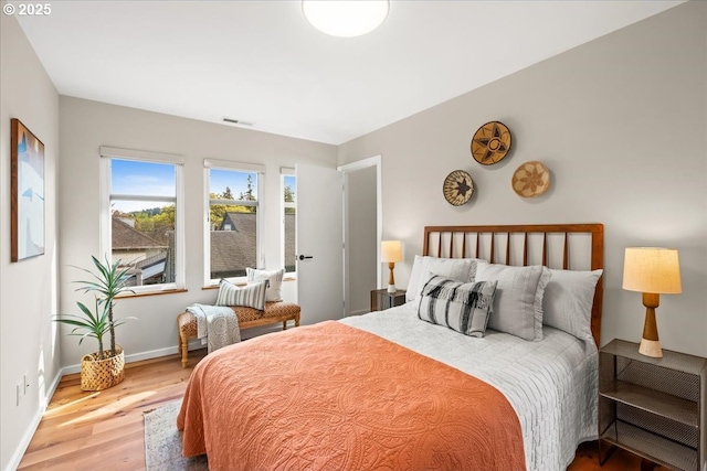 bedroom with visible vents, baseboards, and wood finished floors