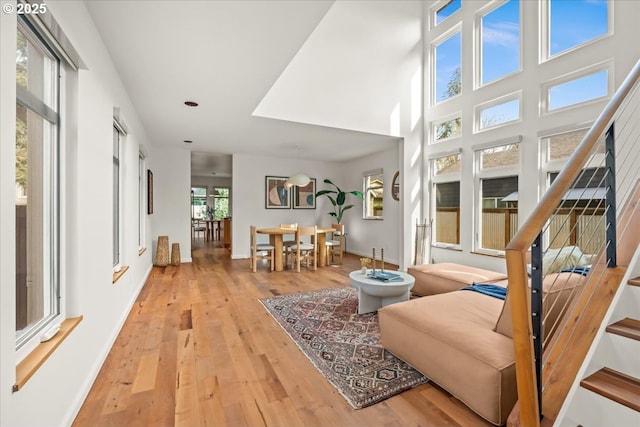 living room with light wood-style flooring, baseboards, and stairway