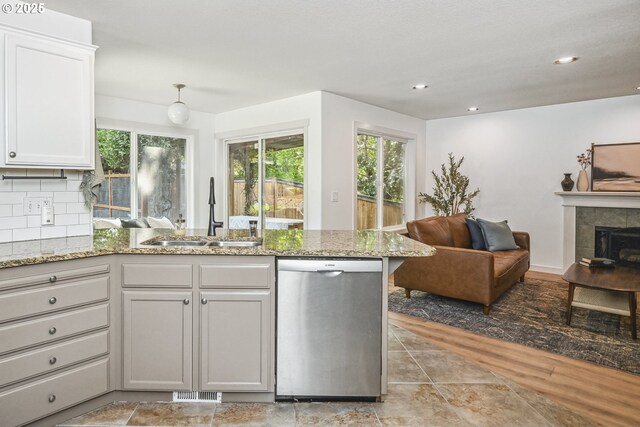 kitchen featuring dishwasher, a sink, a peninsula, open floor plan, and recessed lighting