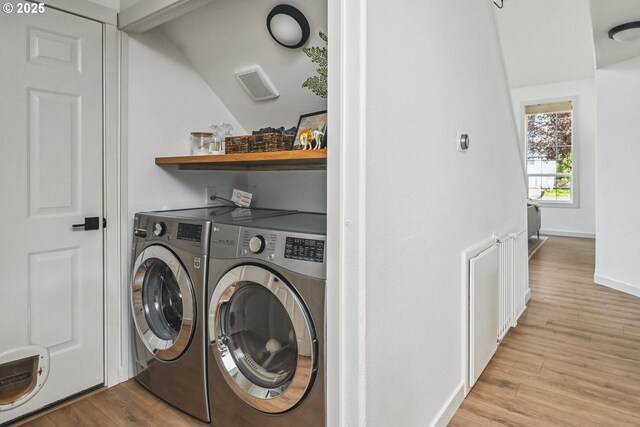 clothes washing area with separate washer and dryer, wood finished floors, and baseboards