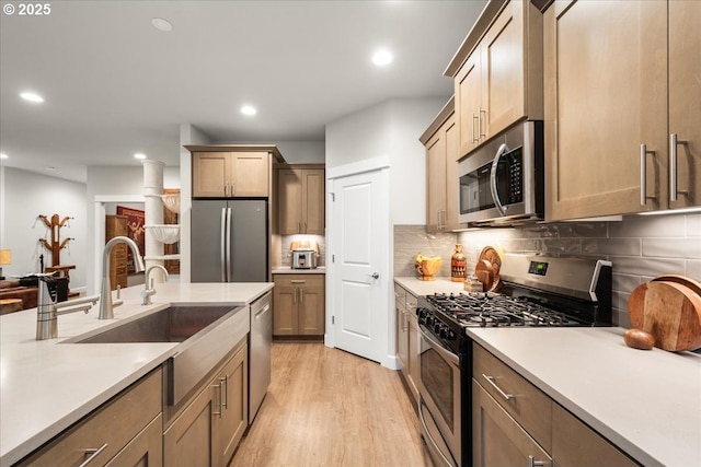 kitchen featuring light wood-type flooring, stainless steel appliances, tasteful backsplash, and light countertops