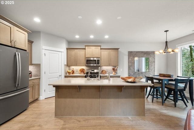 kitchen featuring light countertops, backsplash, light wood-type flooring, and appliances with stainless steel finishes