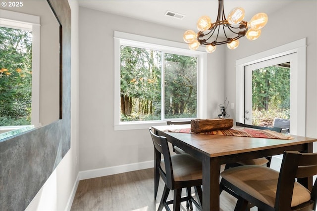 dining room with visible vents, wood finished floors, baseboards, and a chandelier