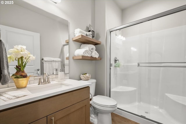 full bathroom featuring vanity, a shower stall, and toilet