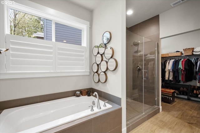 bathroom with a spacious closet, visible vents, a shower stall, and a garden tub