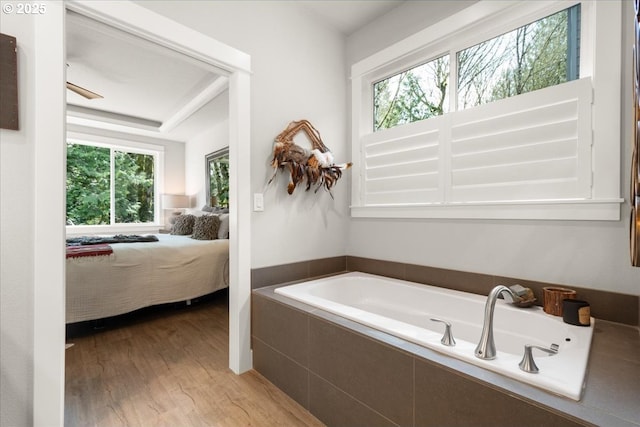 bathroom featuring a garden tub, wood finished floors, and ensuite bathroom