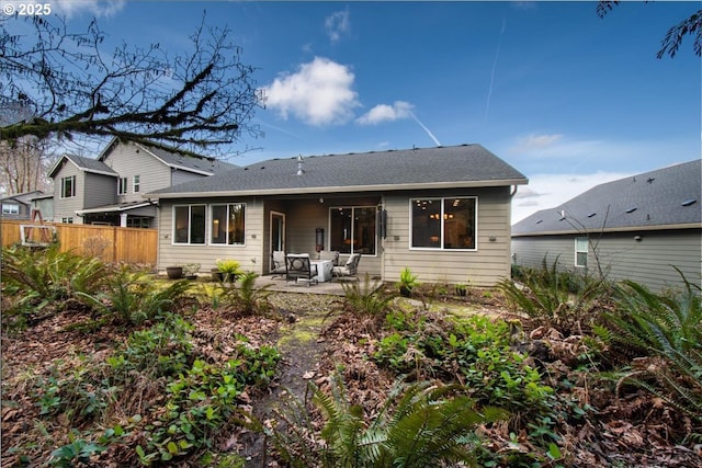 rear view of house with fence, a shingled roof, and a patio area