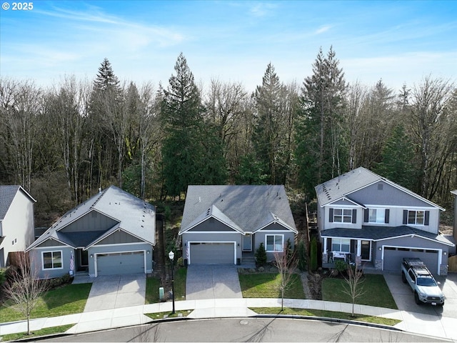 view of front of home featuring a wooded view, concrete driveway, and a front lawn