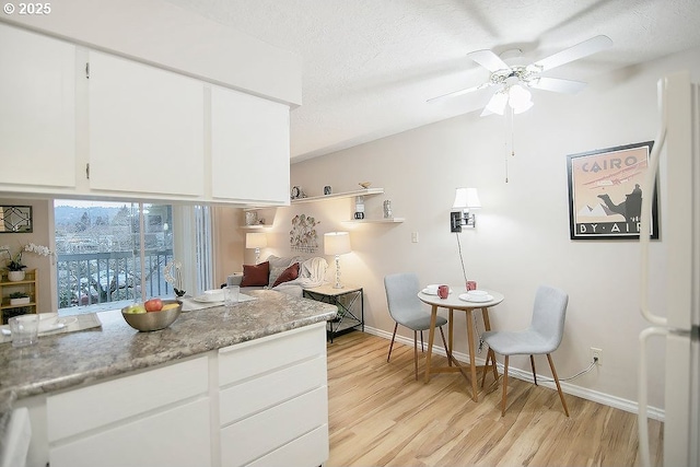 kitchen featuring white cabinetry, white fridge, a textured ceiling, and light stone counters