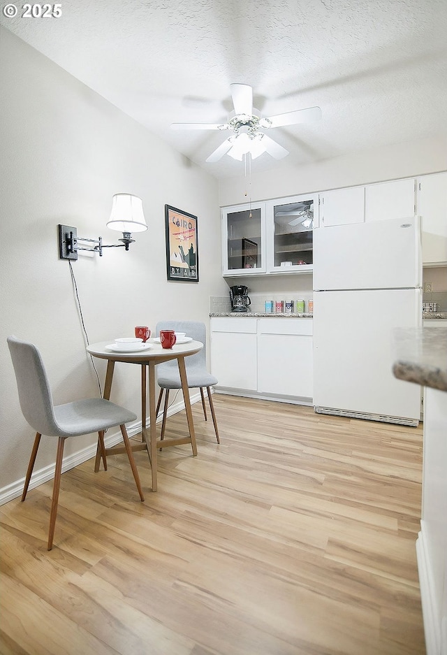 dining room with ceiling fan, light hardwood / wood-style floors, and a textured ceiling