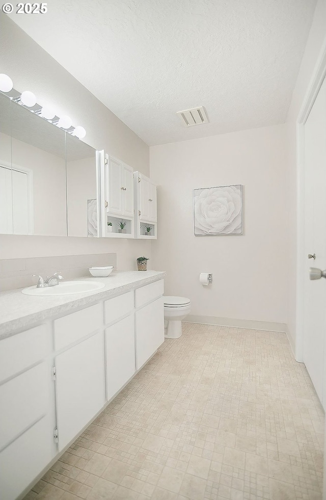 bathroom with vanity, toilet, and a textured ceiling