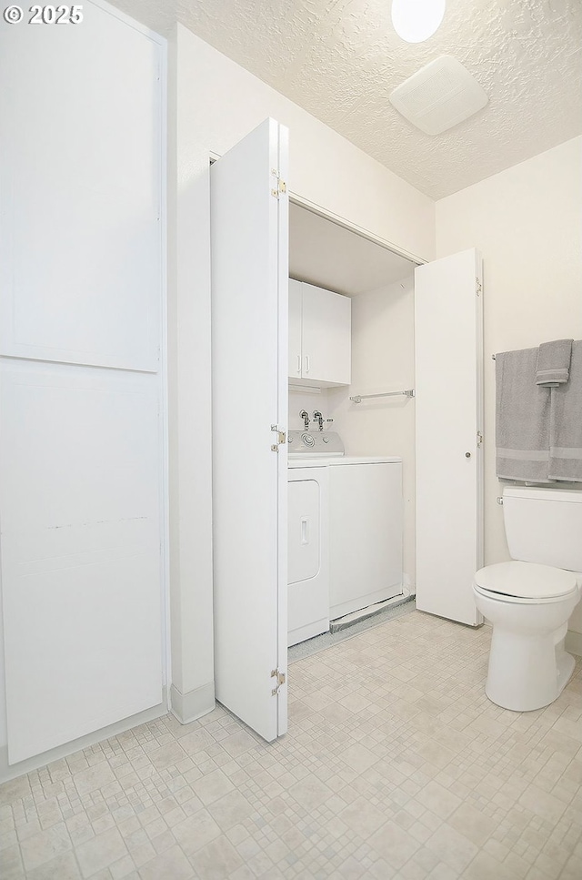 bathroom featuring washing machine and clothes dryer and a textured ceiling