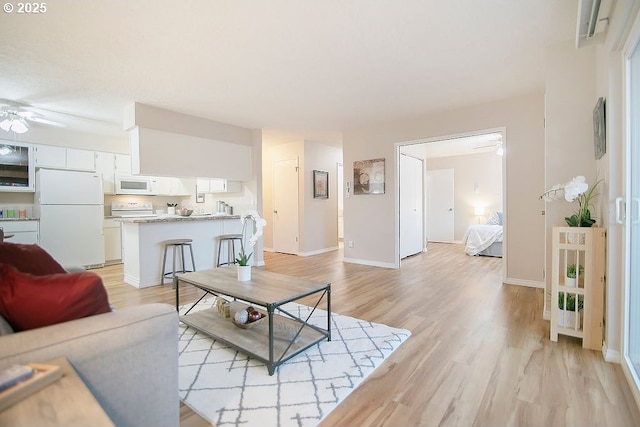 living room with ceiling fan and light hardwood / wood-style flooring