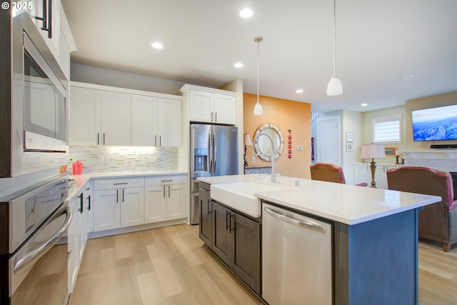 kitchen with sink, white cabinetry, pendant lighting, and appliances with stainless steel finishes