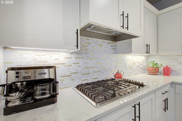 kitchen featuring light stone counters, premium range hood, stainless steel gas cooktop, backsplash, and white cabinetry