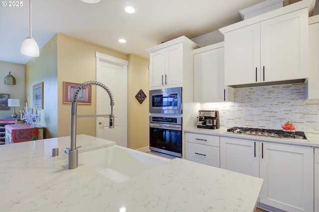 kitchen with stainless steel appliances, white cabinets, decorative backsplash, and decorative light fixtures