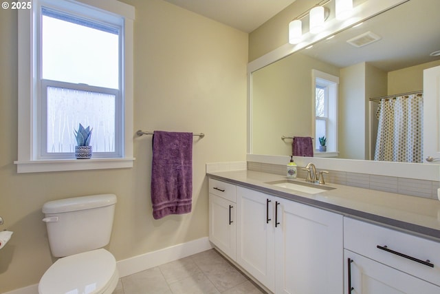 bathroom featuring toilet, tile patterned floors, a healthy amount of sunlight, and vanity