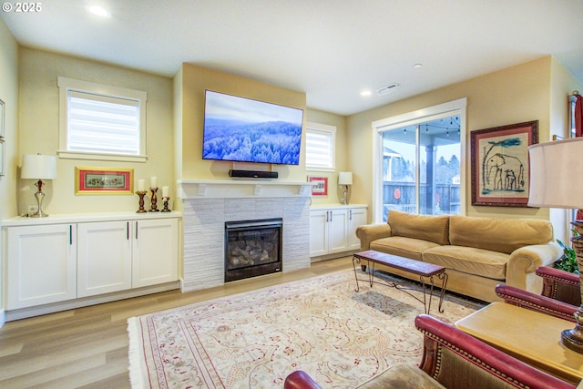 living room featuring a tiled fireplace and light wood-type flooring