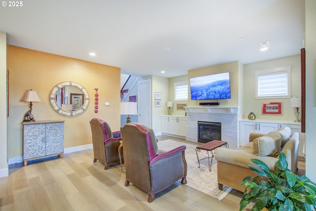 living room with a fireplace, light wood-type flooring, and plenty of natural light