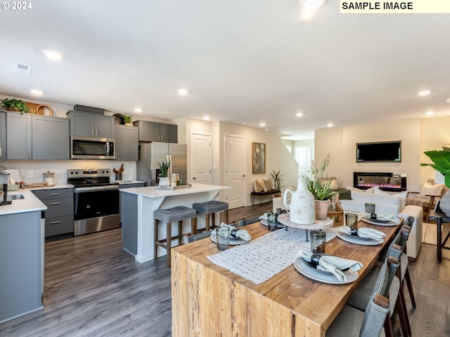 dining space featuring recessed lighting, visible vents, dark wood finished floors, and a glass covered fireplace