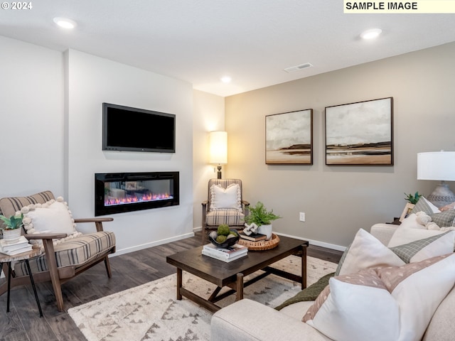 living room featuring recessed lighting, dark wood finished floors, visible vents, baseboards, and a glass covered fireplace