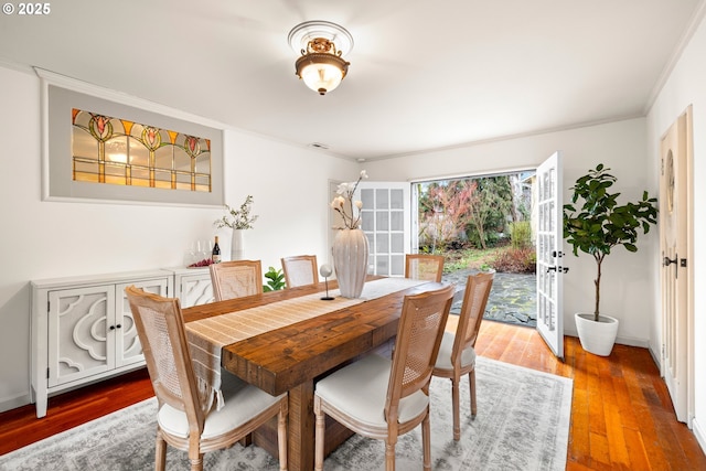 dining space featuring ornamental molding, wood finished floors, and baseboards