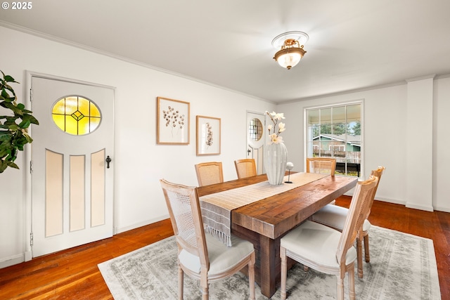 dining room featuring ornamental molding, baseboards, and wood finished floors