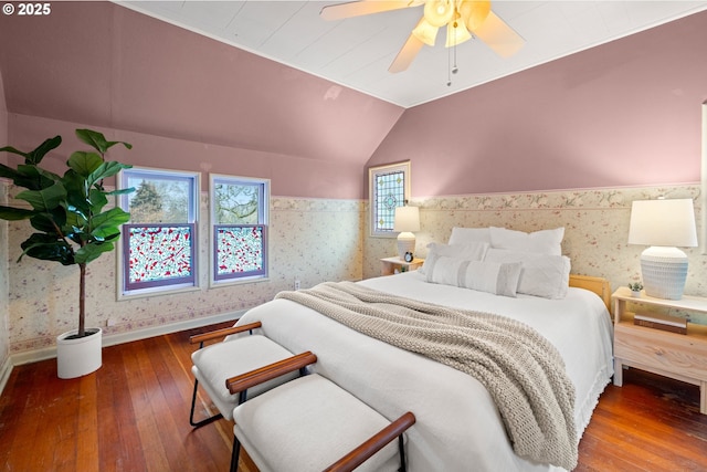 bedroom featuring a wainscoted wall, lofted ceiling, and wallpapered walls