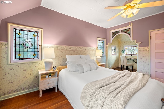 bedroom with wallpapered walls, vaulted ceiling, a wainscoted wall, and wood finished floors