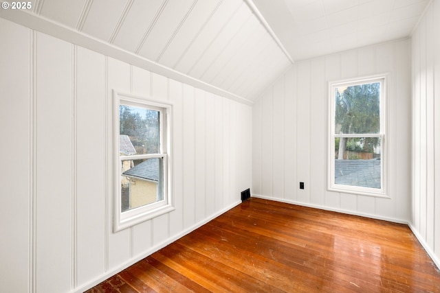 additional living space with vaulted ceiling, wood finished floors, and visible vents