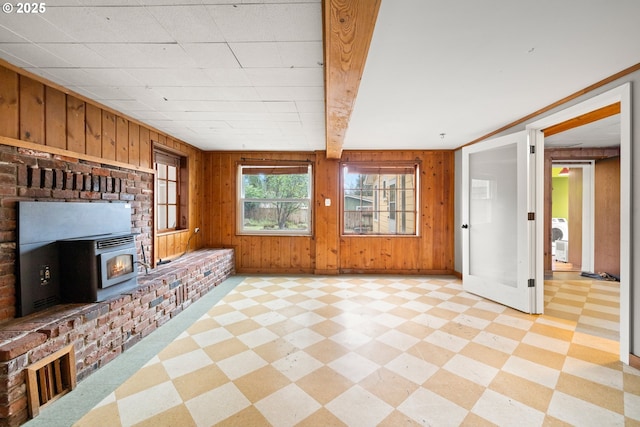 unfurnished living room with light floors, washer / clothes dryer, wood walls, and beam ceiling