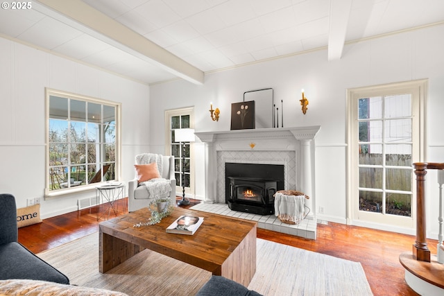 living area featuring beam ceiling, a healthy amount of sunlight, and wood finished floors