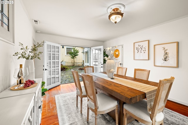 dining space featuring visible vents, crown molding, light wood-style flooring, and baseboards