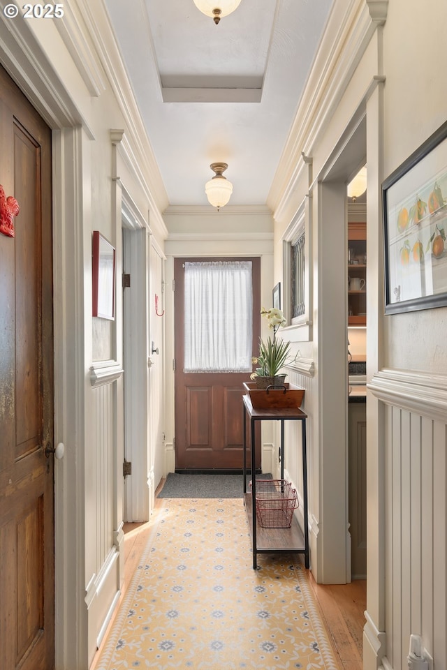 entryway with crown molding, light wood-type flooring, and a tray ceiling