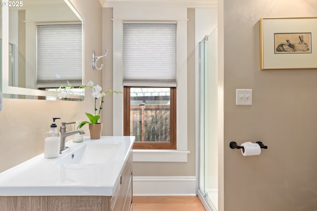 bathroom featuring vanity, wood finished floors, baseboards, and a shower