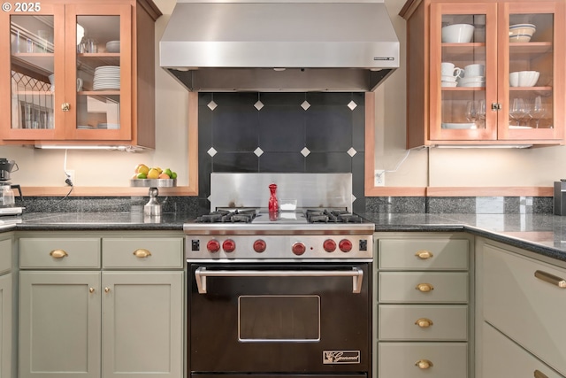 kitchen featuring green cabinets, glass insert cabinets, wall chimney exhaust hood, and luxury stove