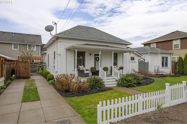 view of front of home with a gate, fence, a porch, a shingled roof, and a front lawn