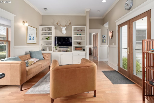 living area with a wainscoted wall, light wood-style floors, and ornamental molding