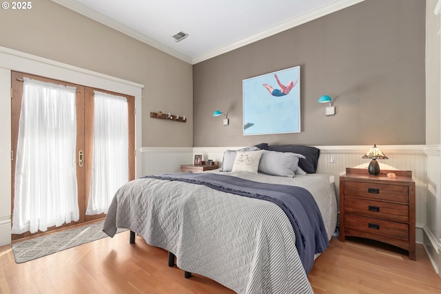 bedroom with visible vents, multiple windows, ornamental molding, and a wainscoted wall