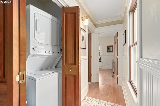 washroom with light wood finished floors, stacked washer and clothes dryer, laundry area, and crown molding