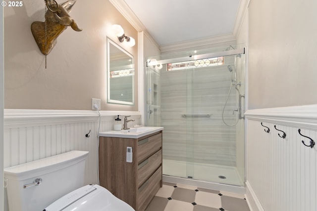 bathroom featuring a wainscoted wall, toilet, a stall shower, ornamental molding, and vanity