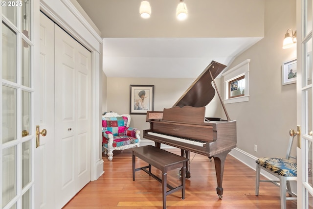 living area with lofted ceiling, light wood-style floors, and baseboards