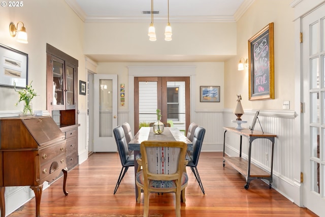 dining area with wood finished floors, visible vents, french doors, and ornamental molding